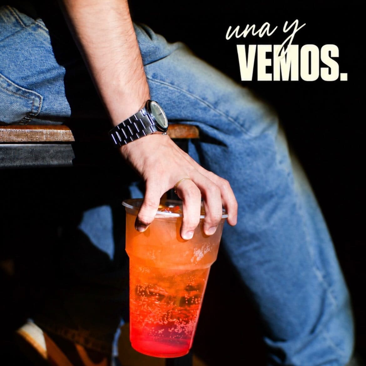 Un trago naranja en la mano, con el texto Una y vemos